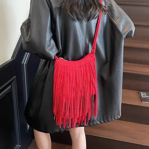 Sac à bandoulière rouge tendance à franges en daim porté par un mannequin en ville