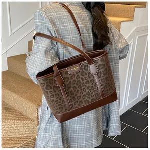 Close-up of leopard print tote bag worn with a plaid blazer on a stone staircase