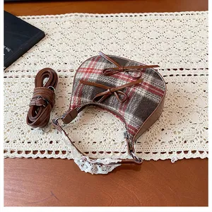 Detail of plaid mini crossbody bag with brown bows and delicate lace trim on wood table