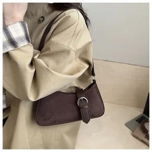 Side view of dark coffee suede underarm bag paired with a classic khaki trench coat