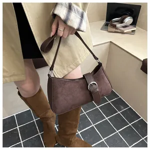 Detail of dark brown suede underarm bag with silver buckle worn with a beige trench coat