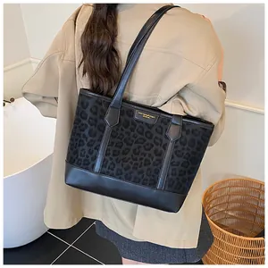Detail of black leopard print tote bag with gold logo on shoulder in home setting