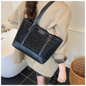Detail showing black leopard print tote bag with glossy leather trim and golden metal logo