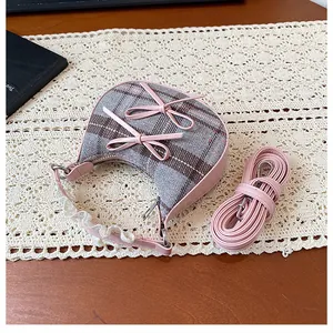Detailed view of plaid mini handbag with pink bows and lace strap on white table