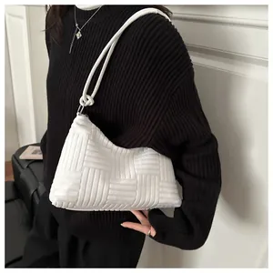 Detail of white textured woven hobo bag with minimalist shoulder strap and plaid pattern