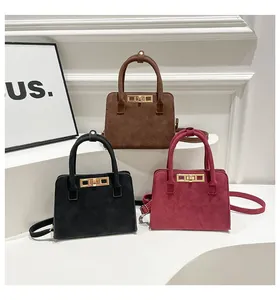 Close-up of matte square handbags in brown, black, and wine red with gold metal buckles