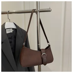 Detail of dark brown suede shoulder bag with silver buckle and leather patchwork