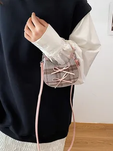 Mini plaid crossbody bag with pink bows shown on model in a stylish outfit