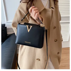 Close-up of black crossbody bucket bag featuring gold V-shaped hardware and logo