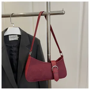 Detail of red suede patchwork shoulder bag with silver buckle and leather strap