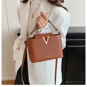 Close-up of brown PU leather bucket bag with V-shaped metal hardware and fashion text