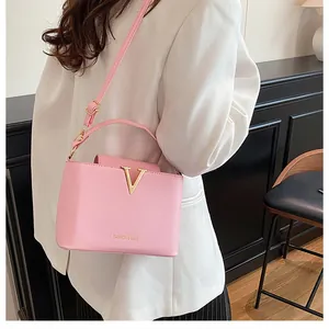 Close-up of pink PU leather bucket bag with golden V decoration and fashion lettering