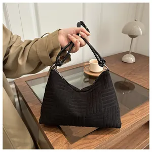 Detailed close-up of the black textured tote bag with silver zipper on a wooden table