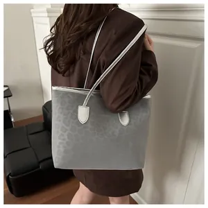 Detail of grey leopard print tote bag with metallic silver trim on brown blazer