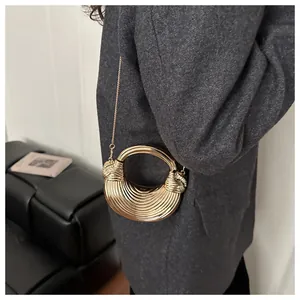 Détail d'un sac coquille doré métallisé avec texture en spirale et poignée ronde