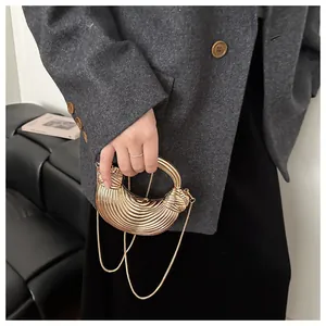 Détail du sac de soirée coquillage doré avec texture rayée élégante et bandoulière chaîne