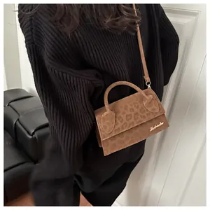Borsa a tracolla leopardata marrone con manico curvo indossata su maglione nero