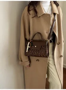 Detail of vintage leopard print baguette bag with beaded charm and brown leather flap