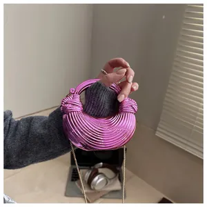 Détail d'un sac coquille en acrylique rose avec texture spirale et chaîne dorée