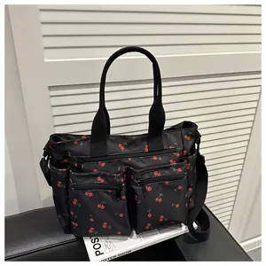 Detail einer schwarzen Nylon-Tragetasche mit Kirschdruck und funktionalem Mehrpasmendesign