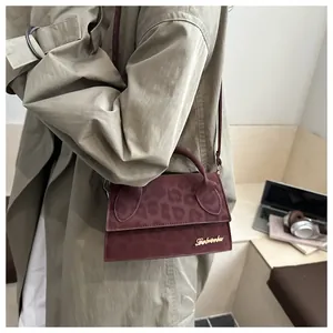 Dettaglio borsa a tracolla bordeaux con goffratura leopardata e logo in metallo dorato
