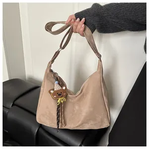 Detail view of khaki hobo bag with adjustable strap and cute bear tassel charm