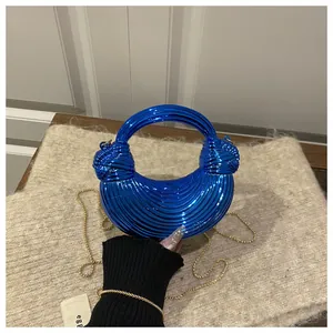 Détail du sac coquille en acrylique bleu avec texture métallique et poignée torsadée