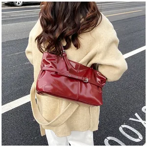 Sac à épaule en cuir verni rouge brillant porté avec un manteau d'hiver beige chic