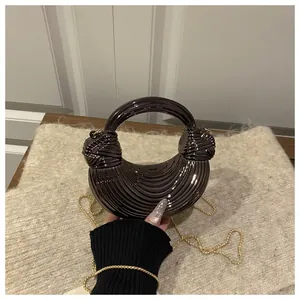 Détail du sac coquille noir métallique avec texture plissée et poignées à nœuds élégantes