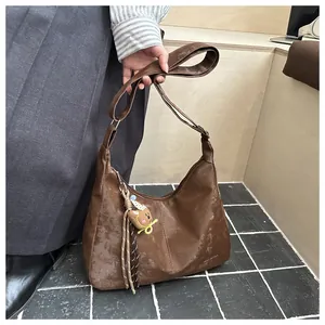 Detail of dark brown crescent bag with teddy bear charm and retro texture finish