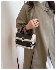 Détail de la garniture en laine d'agneau sur un sac noir avec fermoir en métal doré