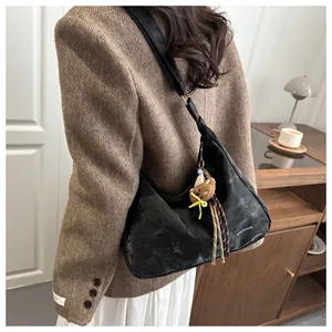 Detail of vintage black hobo shoulder bag with white lettering and cute bear charm
