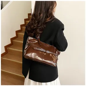 Détail d'un grand sac cabas en cuir verni marron foncé avec boucle argentée et bandoulière