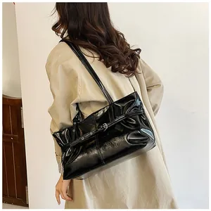 Détail d'un sac à épaule en cuir verni noir brillant avec boucle métallique décorative