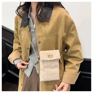 Detail of beige quilted mini crossbody bag with gold chain strap and turn-lock closure