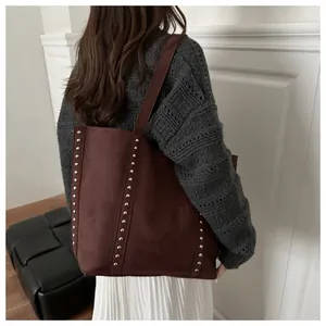 Gros plan d'un grand sac cabas en daim marron avec rivets rétro sur un mannequin femme