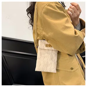 Detail of beige quilted suede mini bag with gold chain strap and rotary lock closure
