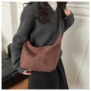 Detailed view of deep brown suede half-moon bag with vertical stitching and leather strap