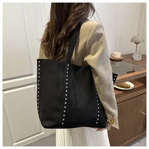 Gros plan d'un sac cabas en daim noir orné de rivets argentés au style bohème chic