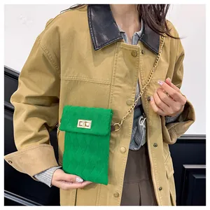 Detail of green quilted mini crossbody bag with golden chain and metal turn lock