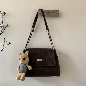 Deep brown matte shoulder bag with silver metal buckle and plush rabbit pendant