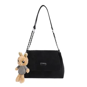 Minimalist black suede shoulder bag with silver chain strap and brown rabbit plush charm