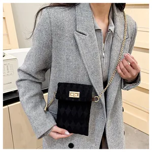 Detail shot of black velvet crossbody bag with gold turn-lock and quilted diamond pattern