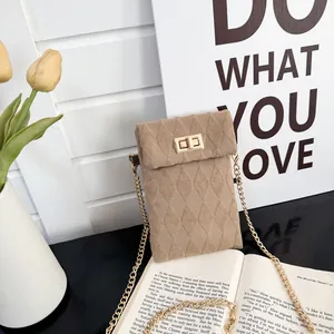Quilted khaki crossbody bag with gold chain and metal lock in a cozy setting