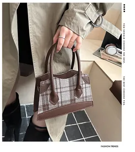 Detail of vintage plaid fabric and brown leather stitching on a mini handbag