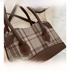 Close-up of brown plaid fabric and premium faux leather details on a stylish bucket bag