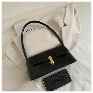 Detail of glossy black leather baguette bag with a premium gold metal buckle fastener