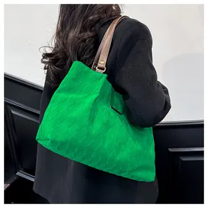 Detailed view of green quilted tote bag with brown leather straps shown on a model