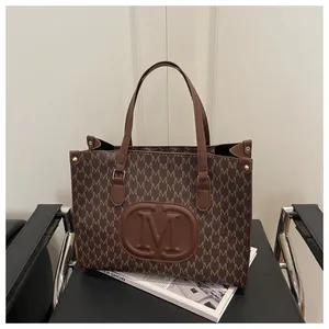 Detail shot of brown tote bag with M-letter pattern and leather embossed logo on black seat