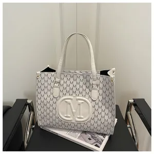 Detailed macro view of the white tote bag with letter prints and embossed M logo